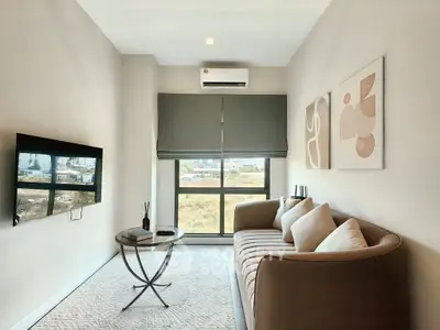 Modern living room with stylish sofa, wall art, and large window offering natural light.