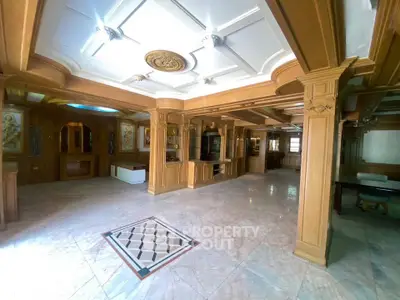 Luxurious living room with intricate wood paneling and marble flooring, featuring elegant ceiling design.