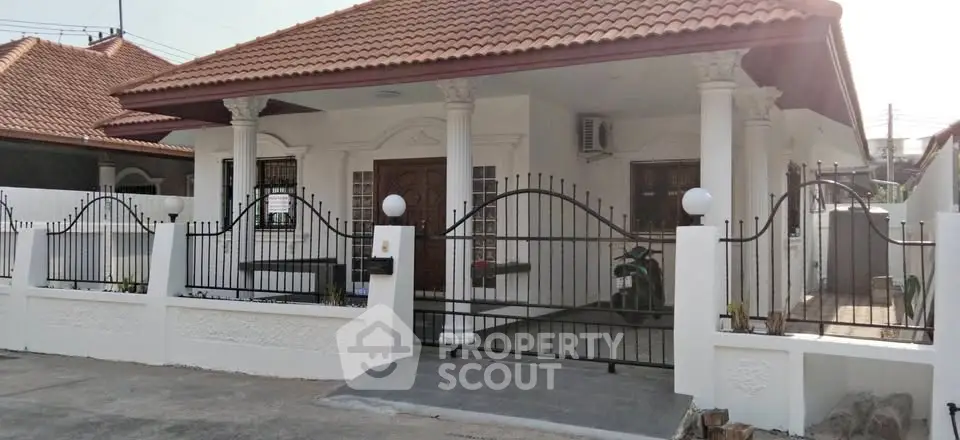 Charming single-story house with tiled roof and gated entrance in a serene neighborhood.