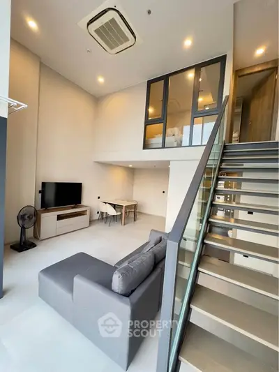 Modern loft apartment with high ceilings, stylish staircase, and cozy living area.