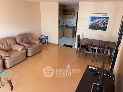 Spacious living room with cozy leather sofa and dining area, adjacent to a compact kitchen.