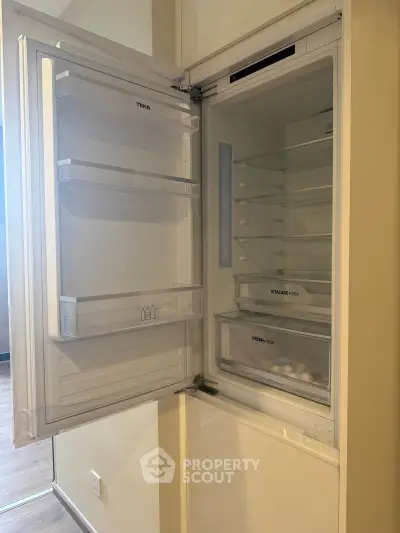 Modern built-in refrigerator with open door showcasing spacious interior in a sleek kitchen setting.