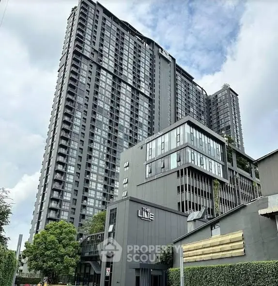 Modern high-rise condominium with sleek design and lush greenery in urban setting.