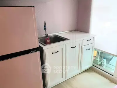 Charming kitchen with pastel pink fridge and sleek white cabinetry, perfect for modern living.
