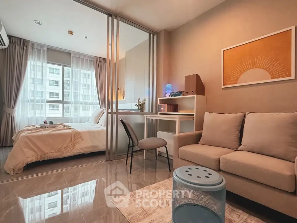 Modern studio apartment with cozy living area and stylish bedroom separated by glass partition.