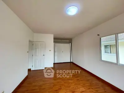 Spacious empty room with wooden flooring and bright lighting