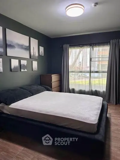 Cozy bedroom with modern decor and large window offering natural light.