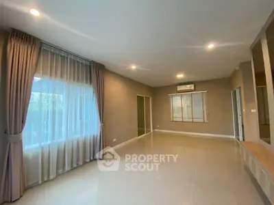 Spacious living room with large windows and elegant curtains, perfect for natural light lovers.