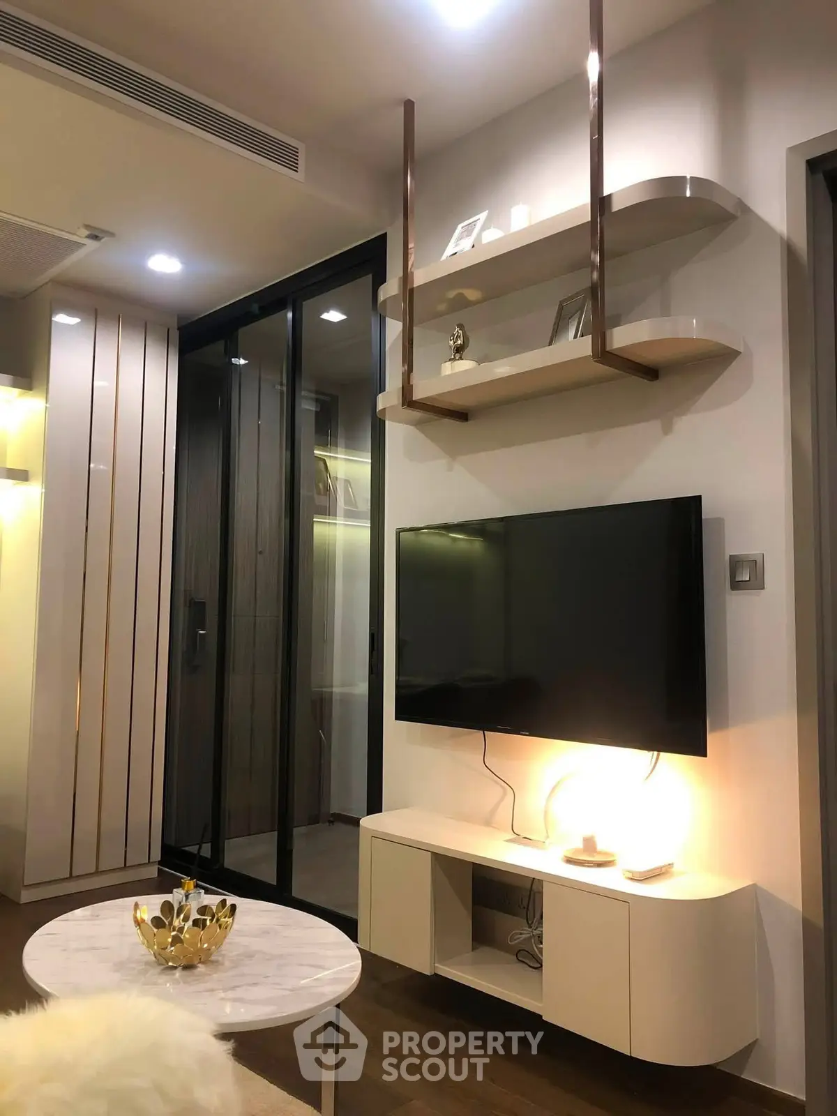 Modern living room with sleek TV setup and stylish shelving in a contemporary apartment.