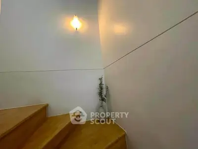Minimalist staircase with wooden steps and elegant wall sconce lighting