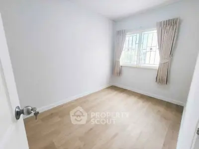 Bright empty bedroom with wooden flooring and large window