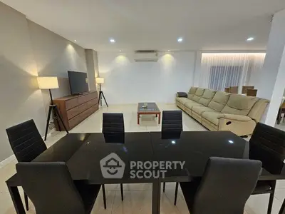 Spacious modern living room with sleek black dining table and cozy beige sofa, perfect for entertaining.