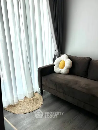 Cozy living room with plush sofa and floral cushion, featuring elegant floor-to-ceiling curtains.