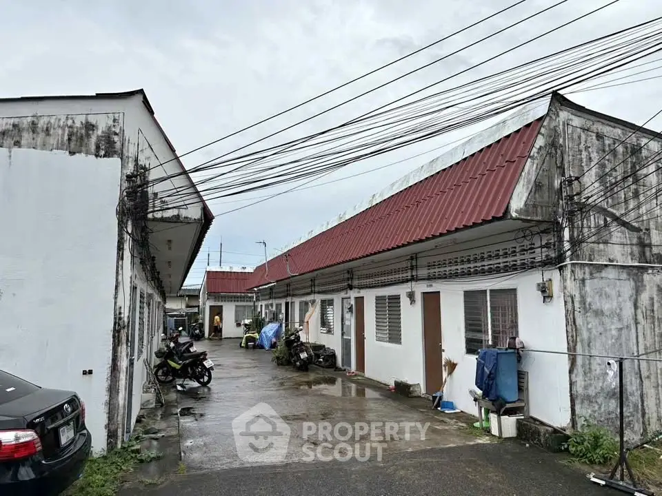 Charming rustic exterior of a residential building with red roof and outdoor parking area.