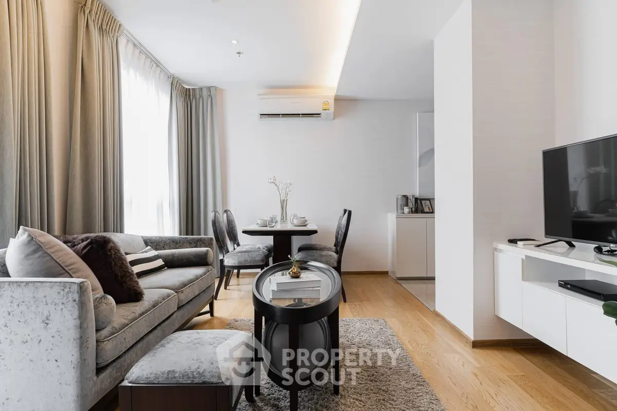 Elegant living room with modern decor, plush sofa, and dining area in a bright, airy apartment.
