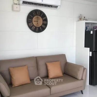Modern living room with stylish sofa and wall clock, featuring sleek air conditioning unit.