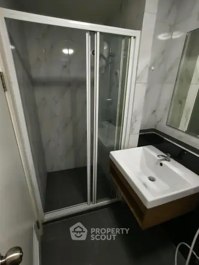 Modern bathroom with sleek shower and stylish sink in contemporary apartment.