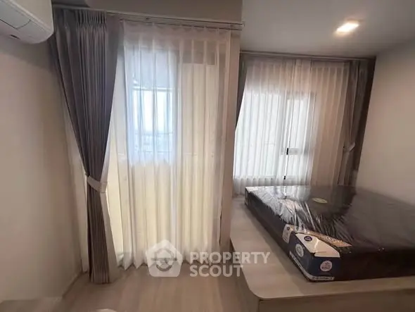 Modern bedroom with large windows and elegant curtains, featuring a new mattress.