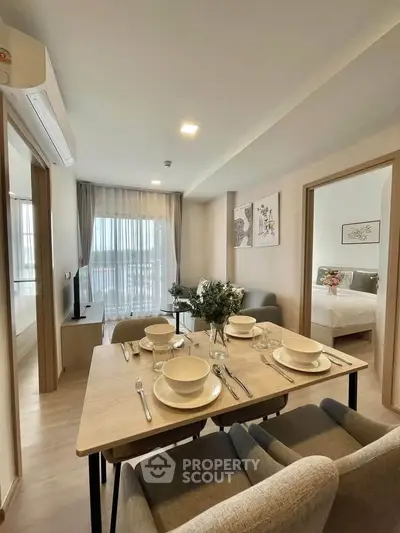 Modern living room with dining area and bedroom view, featuring elegant decor and natural light.