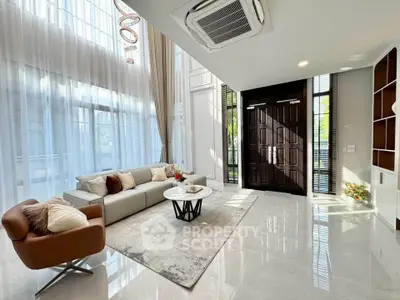 Luxurious living room with high ceilings, elegant furniture, and abundant natural light.