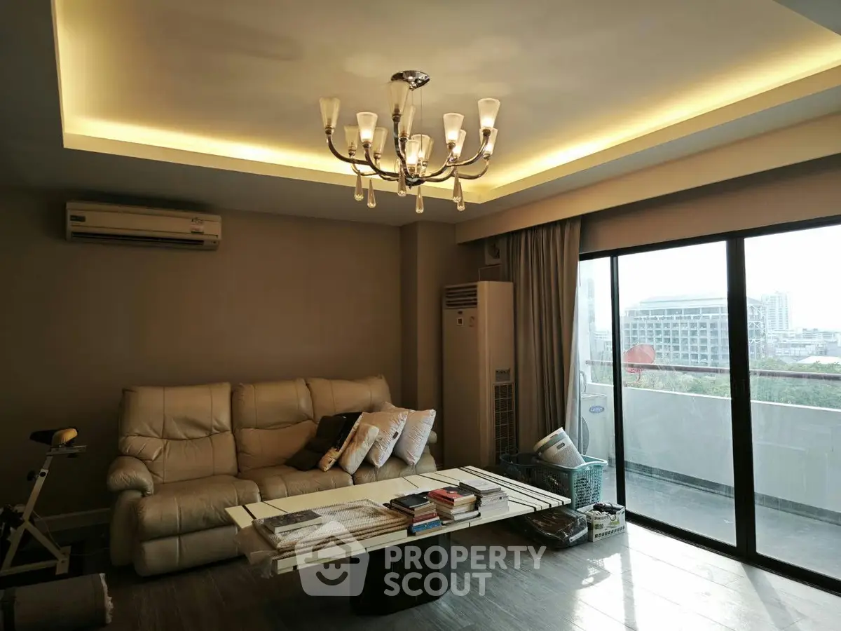 Spacious living room with elegant chandelier and large balcony view