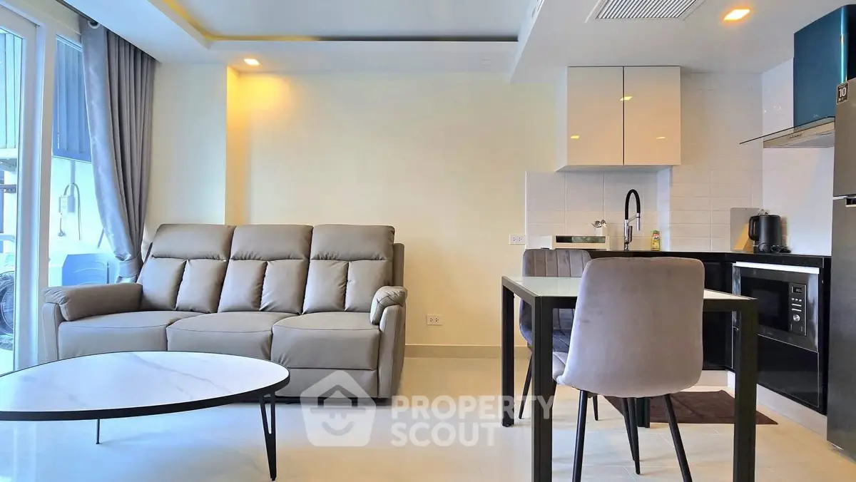 Modern living room with sleek furniture and open kitchen layout in a stylish apartment.