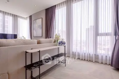 Spacious living room with large windows and elegant decor in modern apartment.