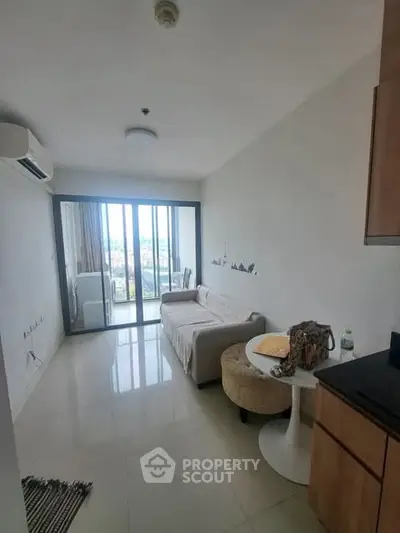Modern living room with balcony view, featuring sleek furniture and abundant natural light.