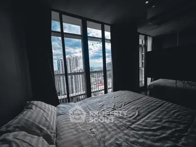 Luxurious bedroom with stunning city view through large windows, featuring modern design and comfort.
