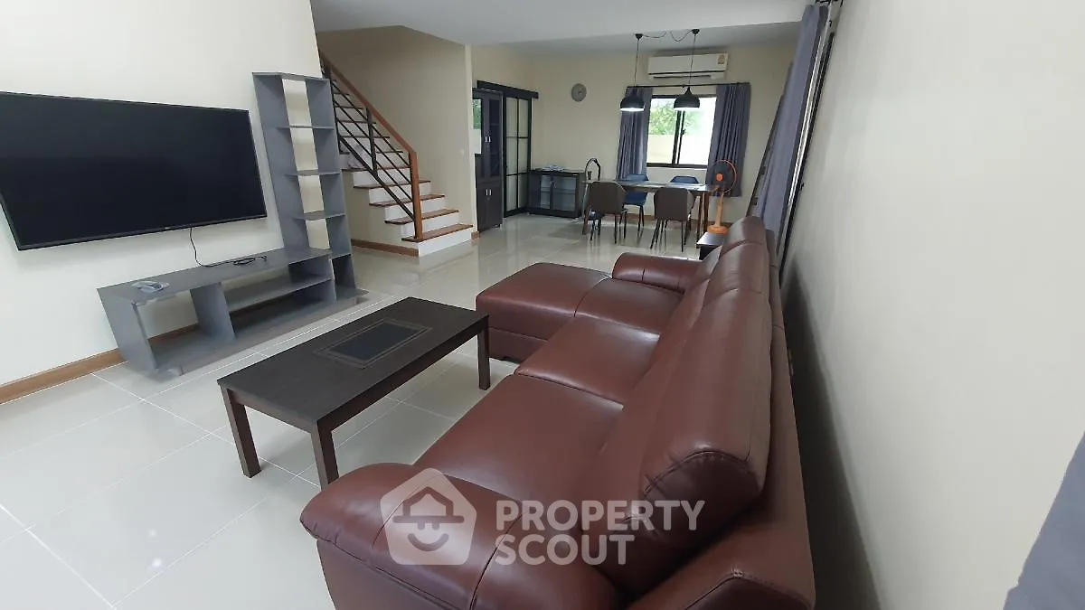 Spacious modern living room with leather sofa and large TV, open layout design.