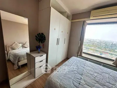 Cozy bedroom with large window offering stunning city view, featuring modern wardrobe and stylish decor.