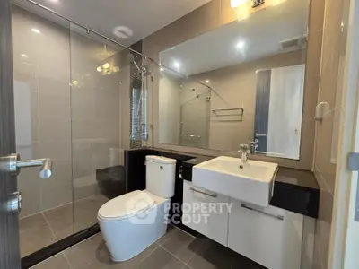 Modern bathroom with sleek fixtures and glass shower enclosure in contemporary apartment.