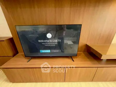 Modern living room with sleek wooden TV stand and flat-screen television.