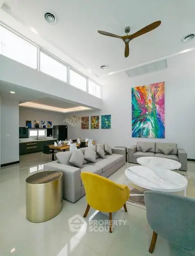 Luxurious modern living room with high ceilings, vibrant artwork, and stylish furniture in a spacious open layout.
