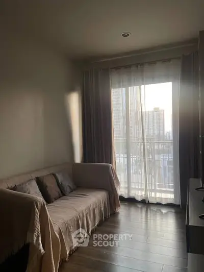 Cozy living room with a sofa and city view through large window, perfect for relaxation.