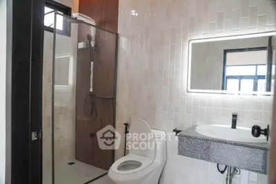 Modern bathroom with glass shower and illuminated mirror in stylish apartment.