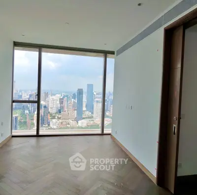 Spacious room with floor-to-ceiling window offering stunning city skyline view.