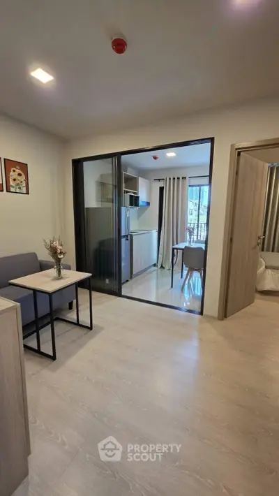 Modern open-plan living room with sliding glass doors to kitchen and dining area, featuring stylish decor.