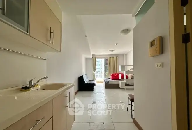 Modern studio apartment with open layout and natural light, featuring a compact kitchen and cozy living area.