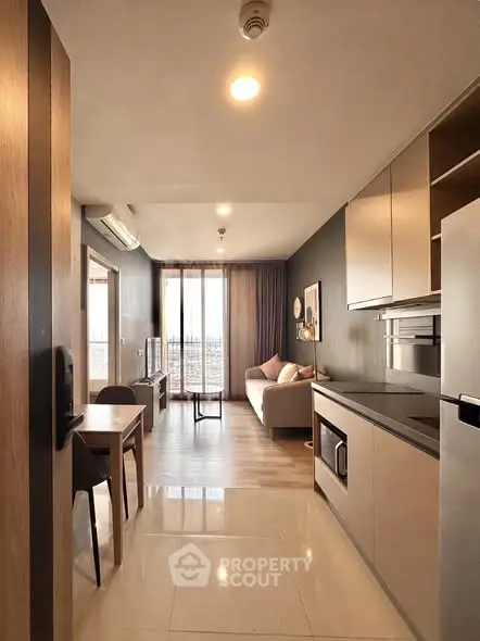 Modern open-layout living room with kitchen, featuring sleek design and natural light.