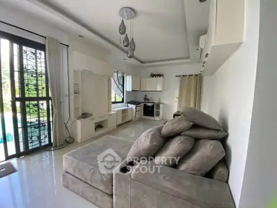 Modern living room with sleek furniture and open kitchen layout, featuring stylish lighting and large windows.