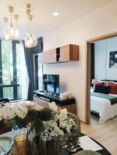 Modern living room with stylish decor and view into cozy bedroom, featuring elegant lighting and natural light.