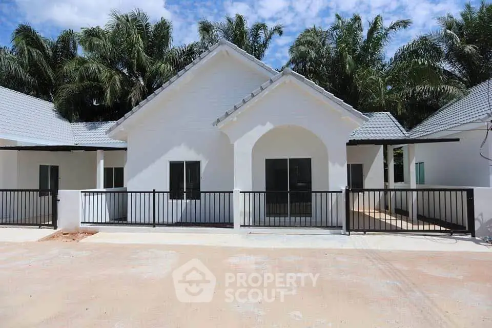 Charming white bungalow with modern design and lush palm backdrop