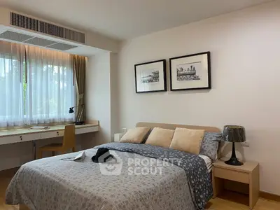 Cozy bedroom with stylish decor and natural light, featuring a comfortable bed and a work desk by the window.