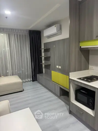 Modern studio apartment with sleek kitchen and cozy living area, featuring stylish cabinetry and air conditioning.