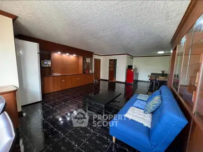 Spacious living room with modern blue sofa and elegant black tiled flooring.