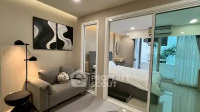 Modern apartment with cozy living room and stylish bedroom separated by glass doors.