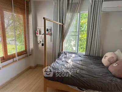 Cozy bedroom with large windows and natural light, featuring stylish decor and comfortable bedding.