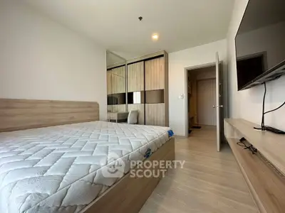 Modern bedroom with wooden furniture and wall-mounted TV in a stylish apartment.