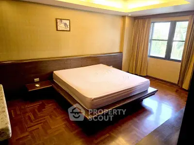 Spacious bedroom with wooden flooring and large window for natural light